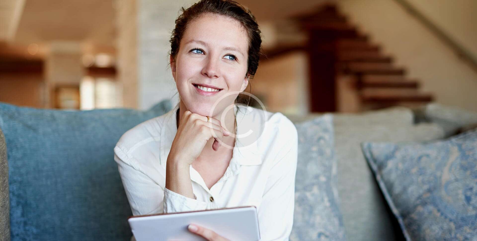 Smiling woman holding a tablet, looking thoughtful.