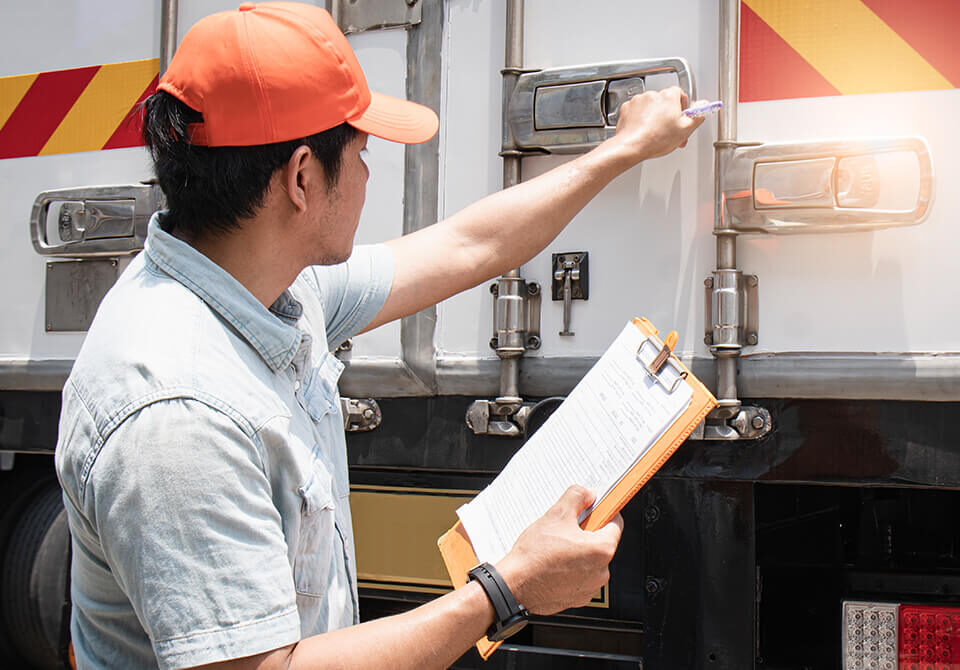 Technician inspecting industrial equipment with clipboard in hand.