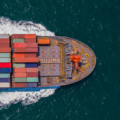 A cargo ship loaded with colorful containers sailing through blue waters.