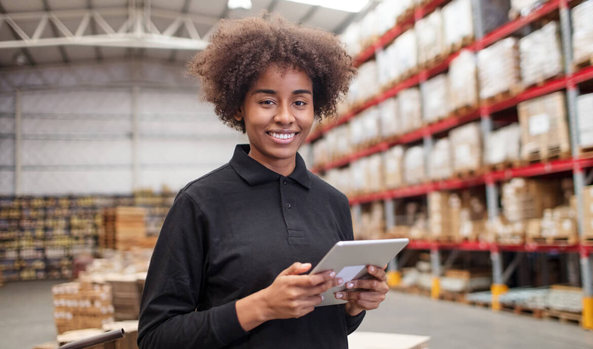 Smiling warehouse worker holding a digital tablet.