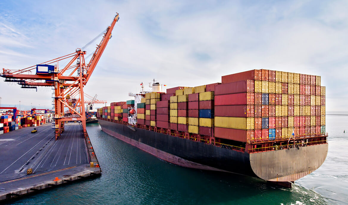 Cargo ship docked with colorful shipping containers and cranes.